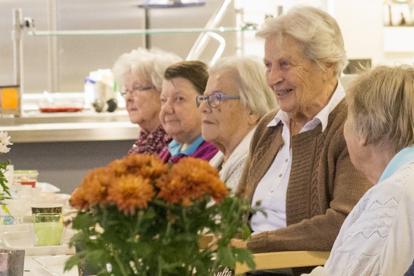 Seniorit istuvat kahvipöydässä nautiskelemassa iltapäiväkahveista.